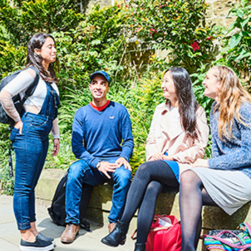 A group of four international students sat on a wall