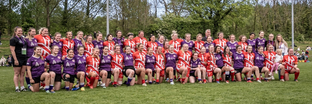 Two female rugby teams in two lines wearing red and white, and purple jerseys