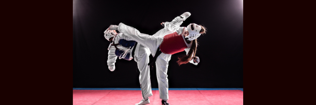 Two martial arts competitors with white sports wear one with a red protective vest, the other with a blue protective vest