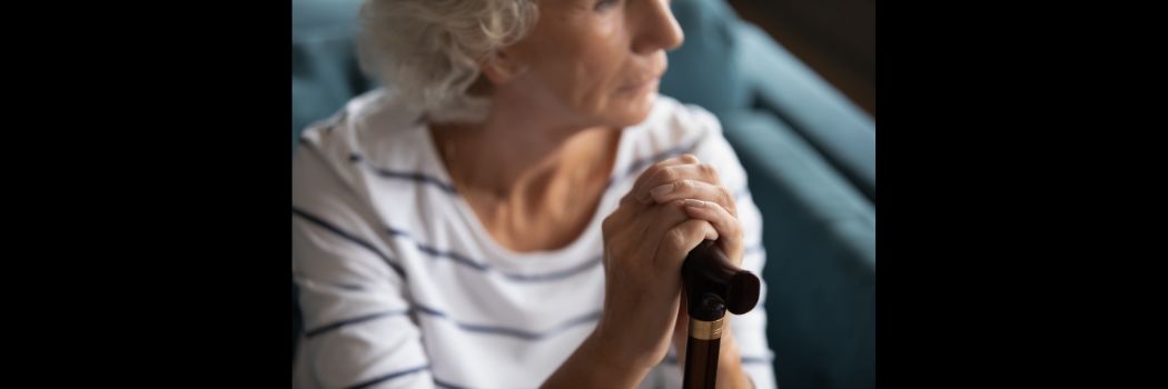 An older woman holding a stick