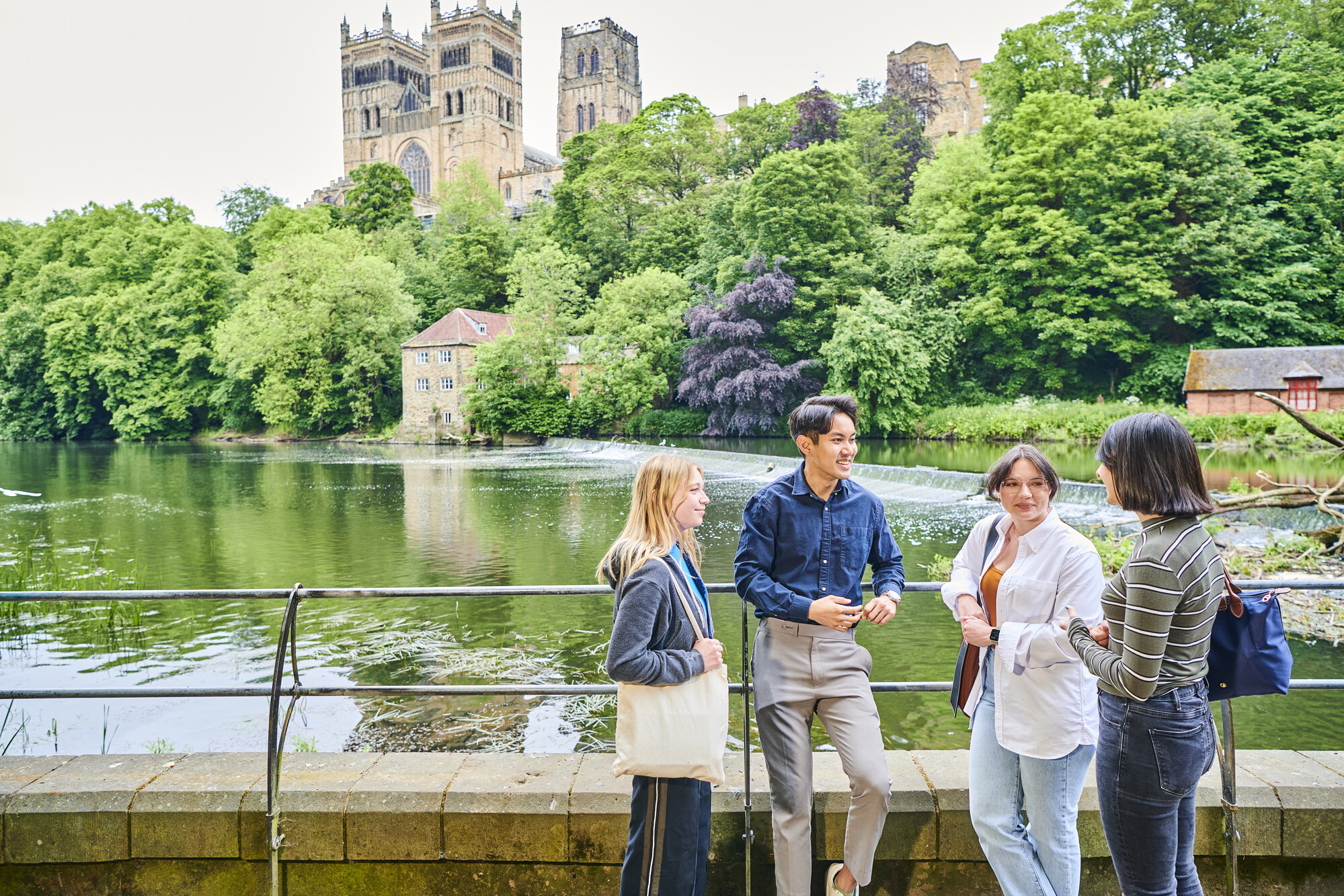 Four students standing by the river with Durham Cathedral in the background