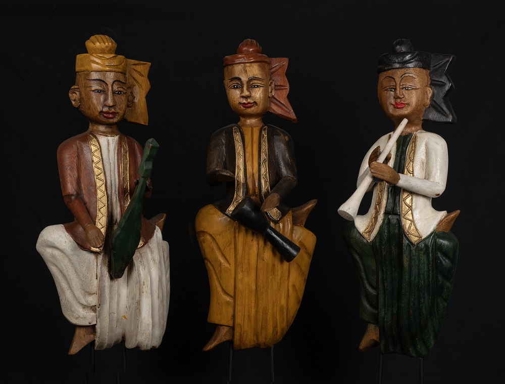 three carved wooden statues each holding a musical instrument