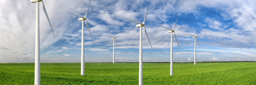 Wind turbines in a grass field with a blue sky