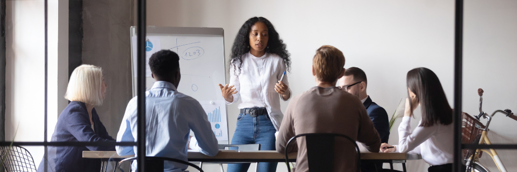 Black woman giving corporate presentation in front of a multiracial team