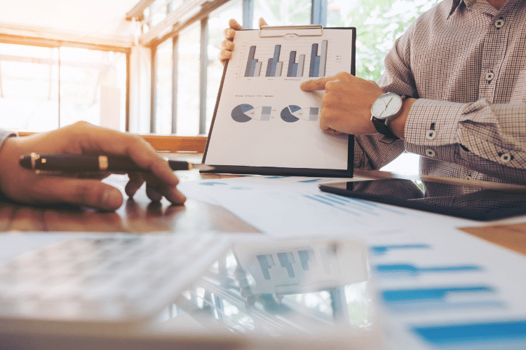 Two men pointing to an economics graph