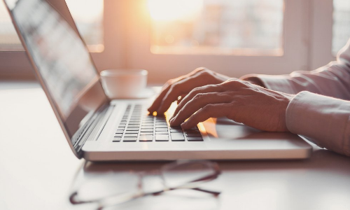 Hands typing on a laptop keyboard