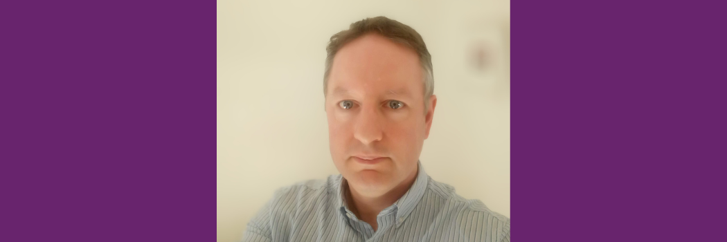Professor Chris Greenwell poses for a portrait in front of a beige background