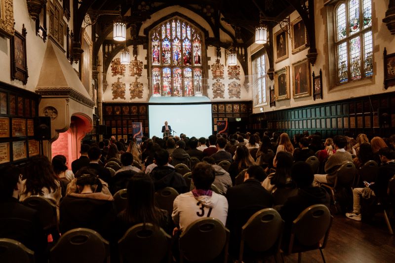 An image taken from the back of the room showing an audience listening to a talk at the welcome for International students
