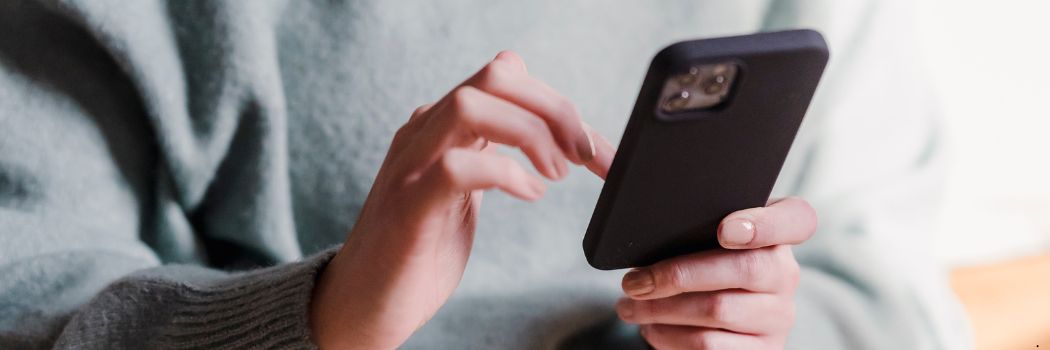 Close up of a woman's hands as she scrolls through a mobile phone