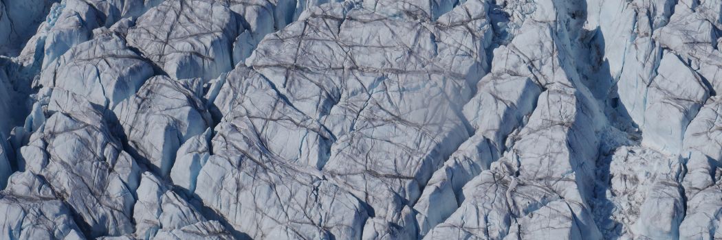 Overhead view looking down on crevasses criss-crossing part of the Greenland Ice Sheet.