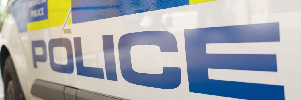 Close up of the side of a British police van with police written in blue against a white background