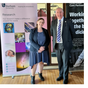 Professor Charlotte Clarke standing next to a man in front of research banners
