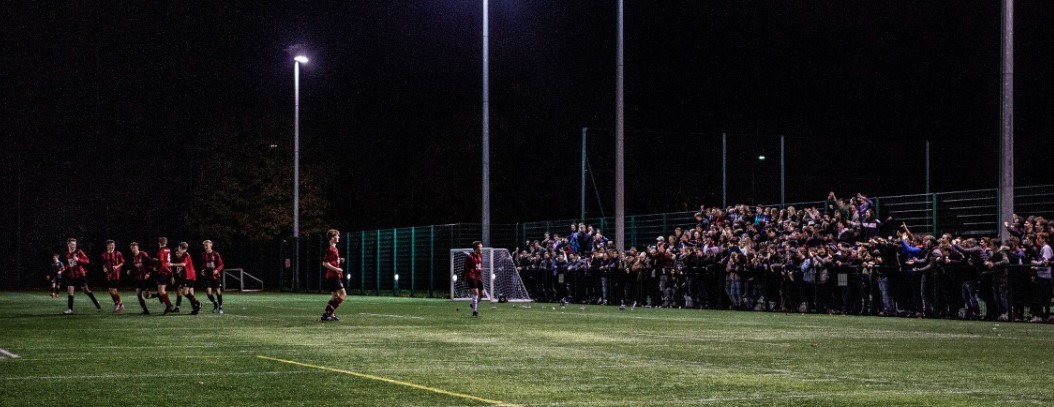 Students cheering on players at a football match