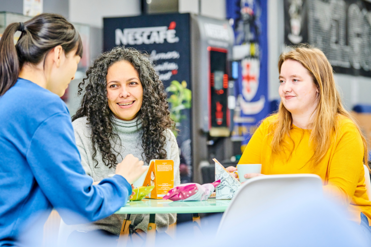 3 Ustinov students, chatting around a table