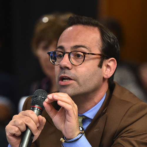 A man wearing glasses talking into a microphone