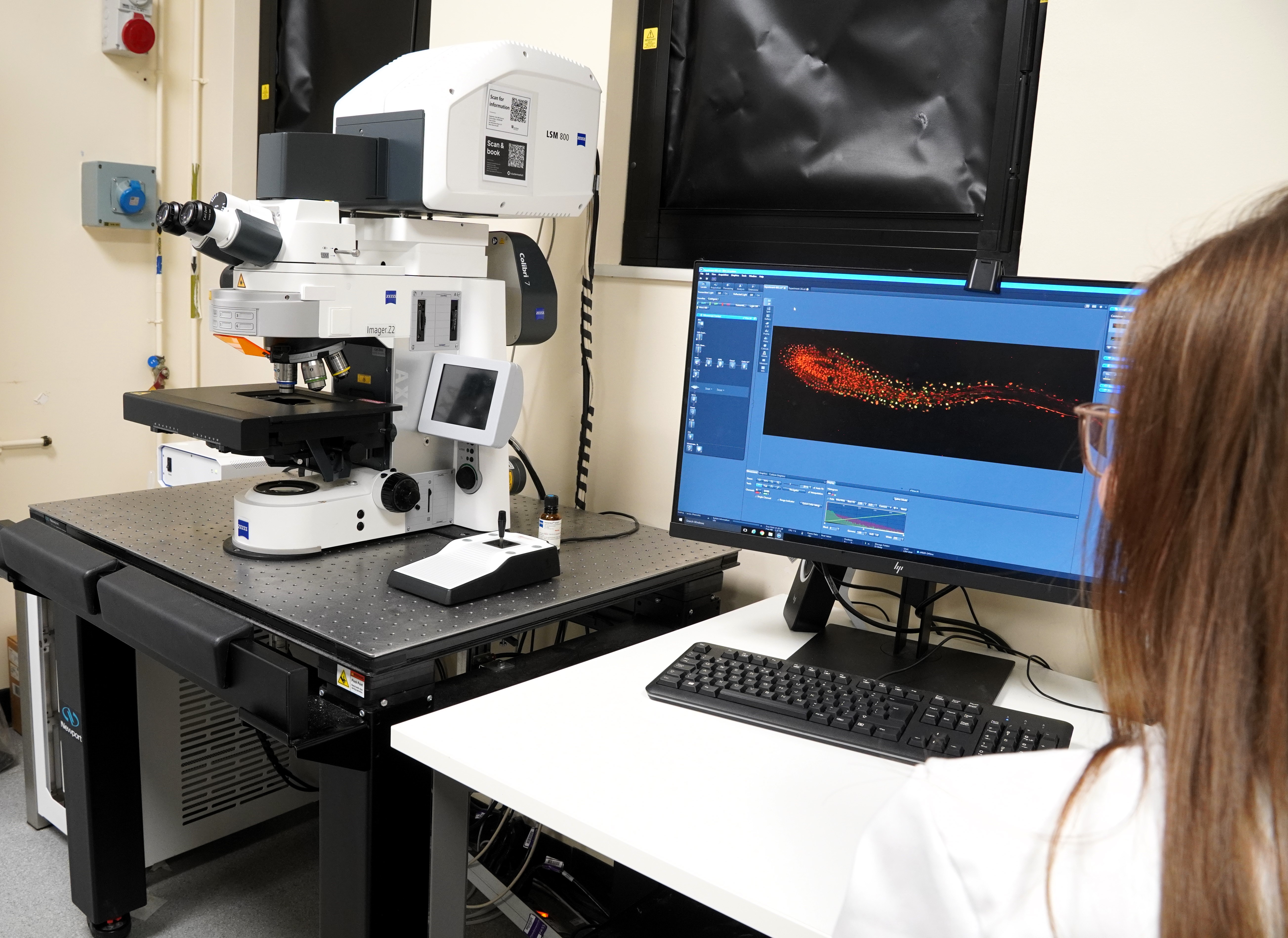 a student sitting at a confocal microscope