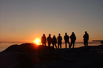 Student group silhouettes against a sunset