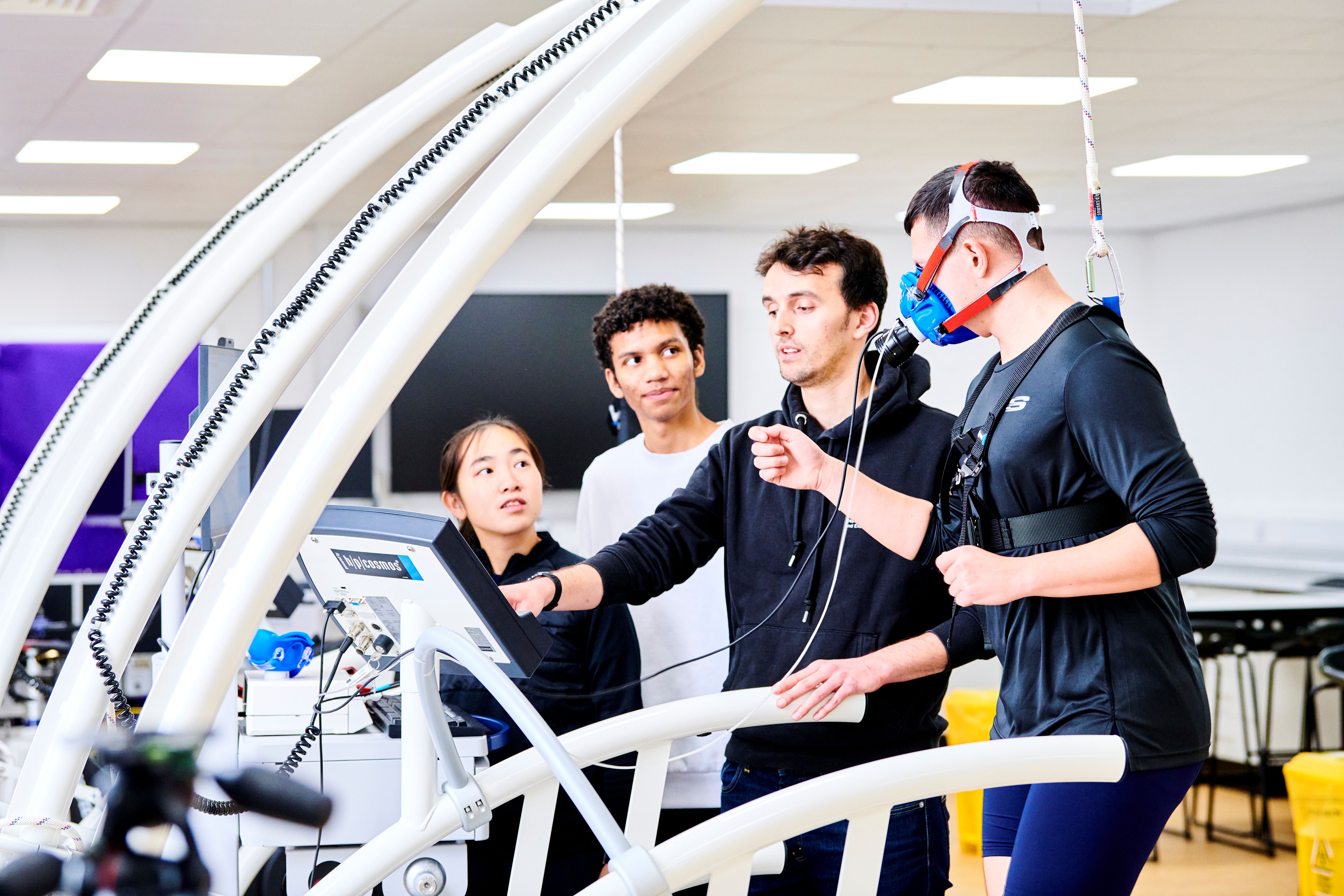 Staff member explaining data to students while a student runs on a treadmill