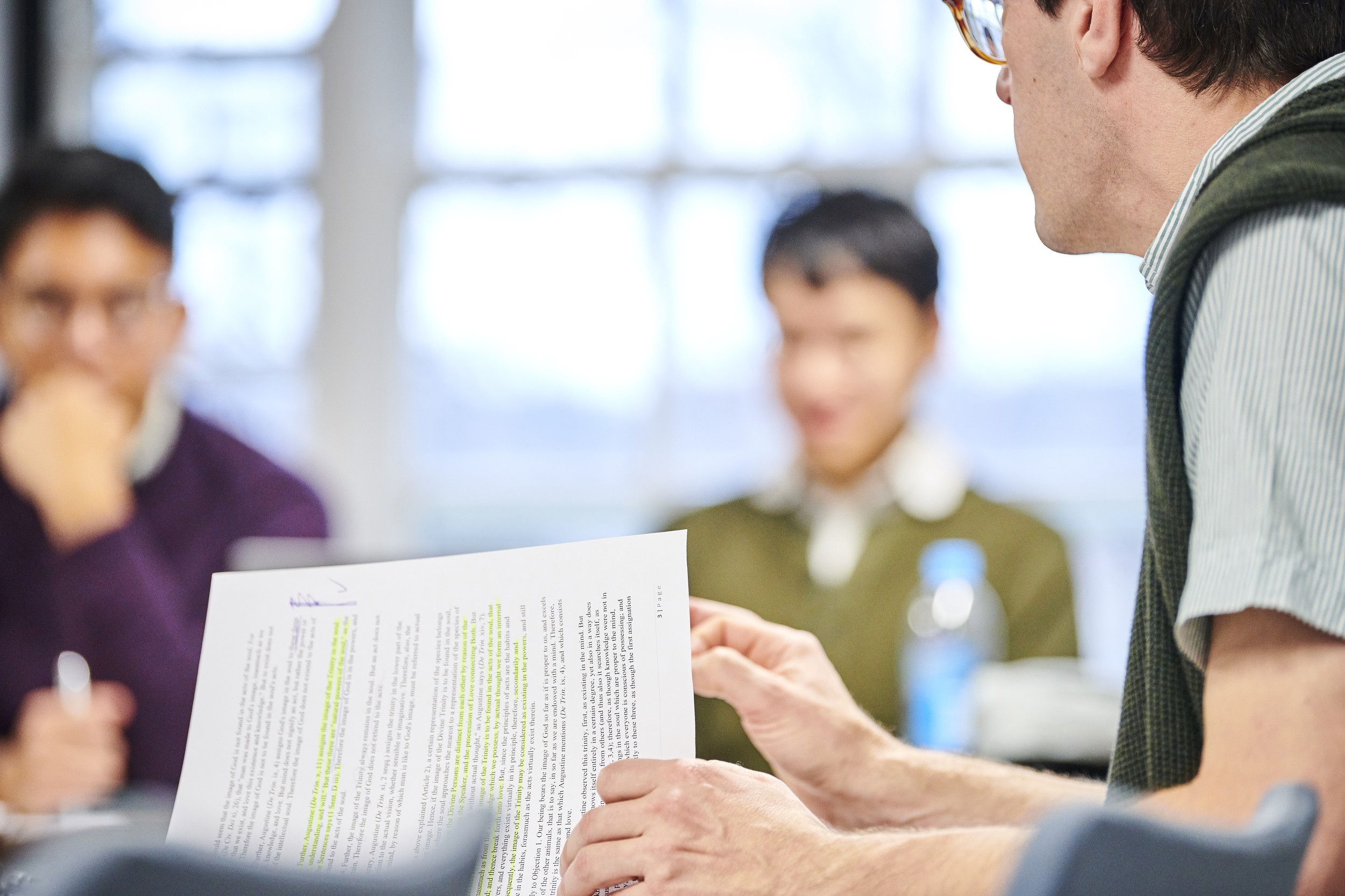 Three people sat round a table going through a paper