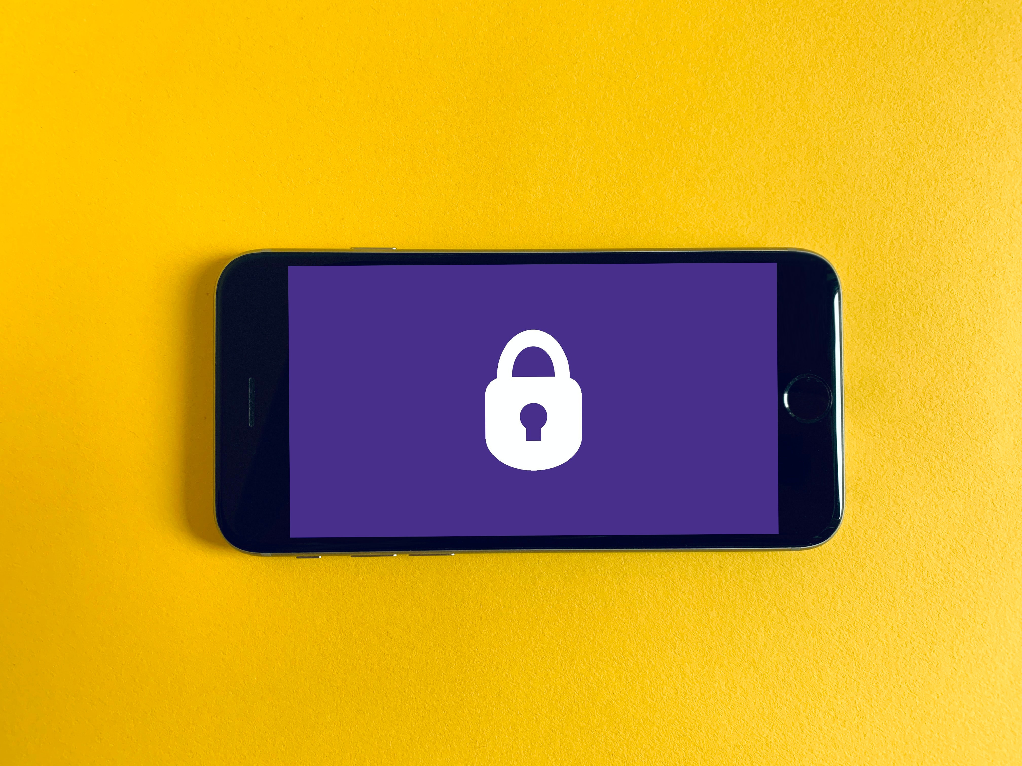 Mobile phone with purple screen and a white padlock on an orange background