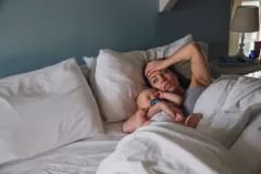 Sleep Deprived Mother with baby in bed