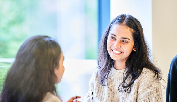 Two happy students sitting together and talking.