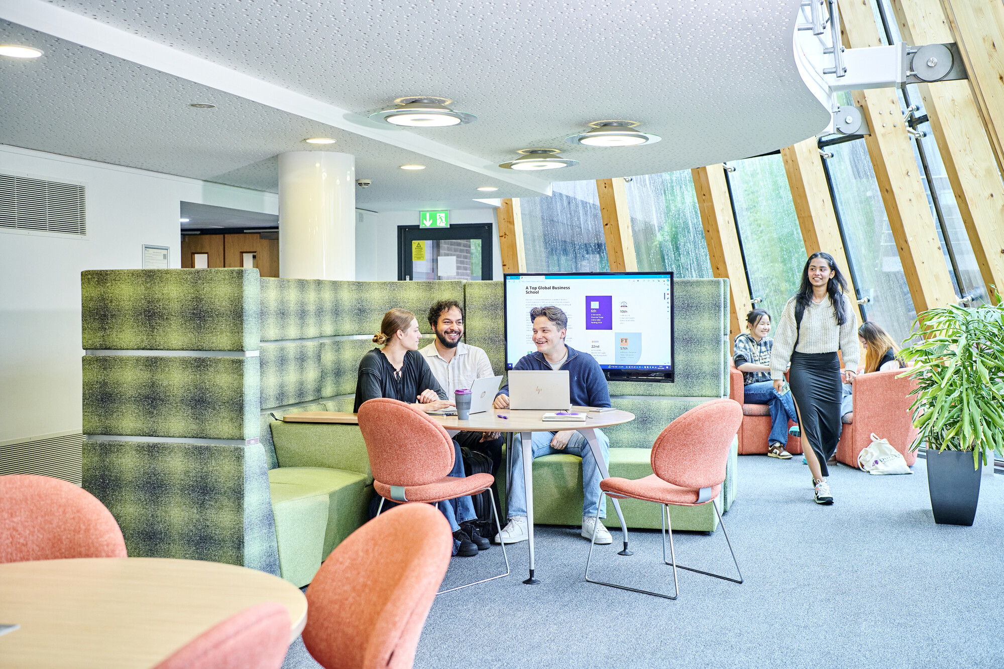 Groups of postgraduate students sit in a modern, airy study space