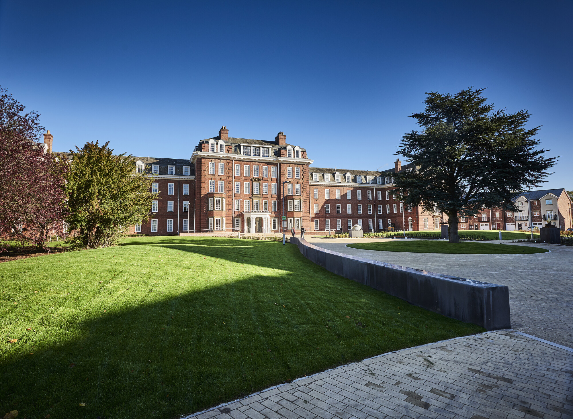 Red brick building with green grounds and a clear sky