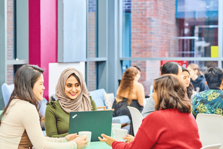 A group of female students sat around a table with a laptop